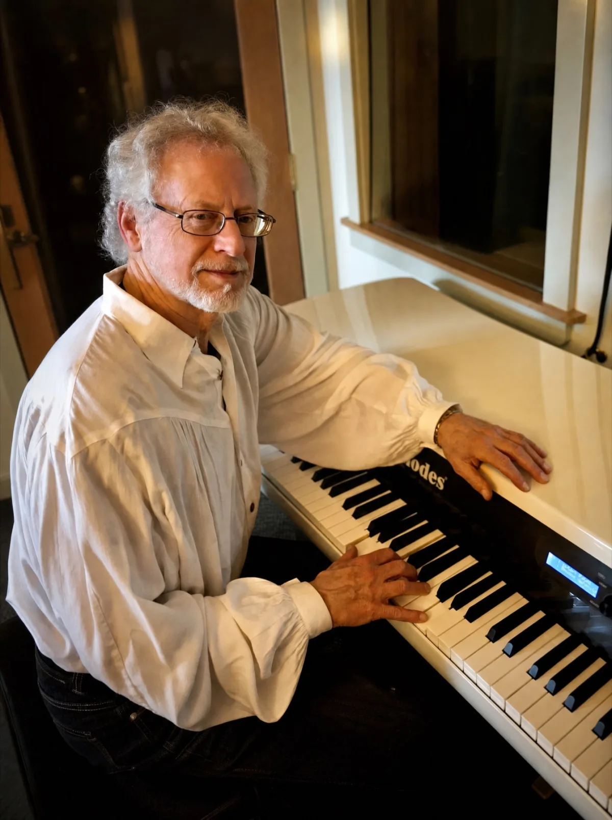 Steven Halpern at his keyboard in a white shirt, warm light.